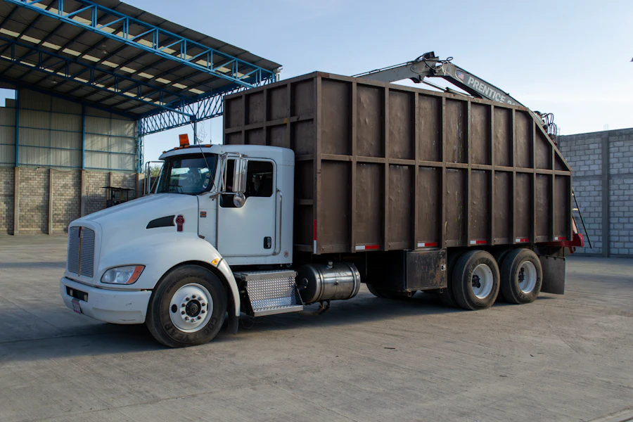 White truck fitted with a tall waste container and loader arm
